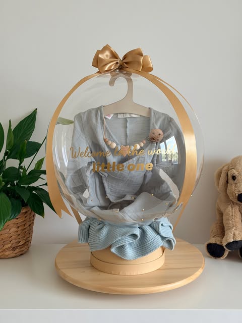 Mušelínové oblečenie na vešiačiku v bubline s nápisom Welcome to the world little one